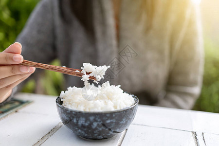 亚裔妇女拿着子煮的茉莉米饭碗背景图片