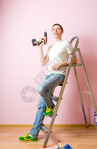 粉色墙背景的在梯子附近钻图片