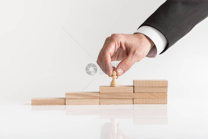 职业管理的概念形象一个商人把棋子象棋片放在一层木砖的楼梯上而图片