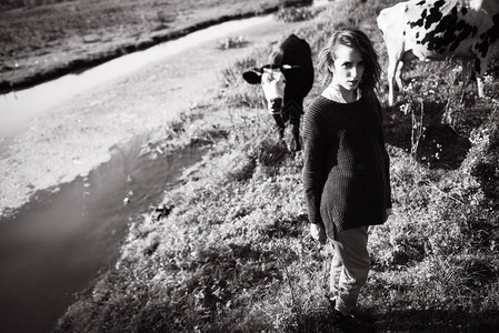 女人站在草地上带着牛黑白相间图片