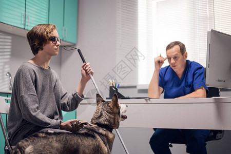 一个盲人女孩带着一条导盲犬向兽医寻求专业建议图片