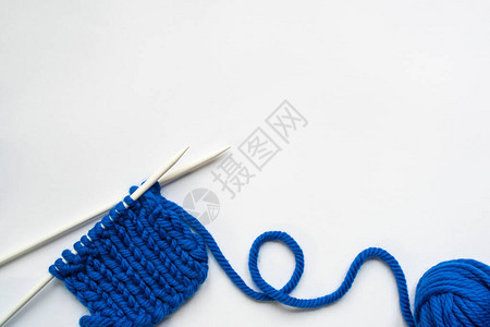 白色背景上蓝色羊毛纱和织针的顶部视图图片