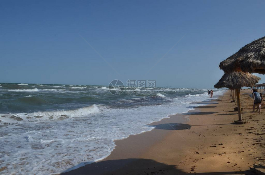 图片描绘了海上的风暴海滩是空的没有游客几人望着汹涌的大海图片