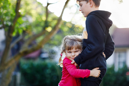 可爱的蹒跚学步的女孩拥抱哥可爱快乐的孩子拥抱小男孩爱家庭和团背景图片