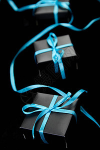 有蓝色丝带的豪华黑色礼物盒在闪耀的黑色背景图片