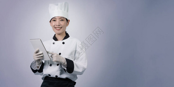 中年亚洲女厨师手持智能手机或数字平板电脑背景图片