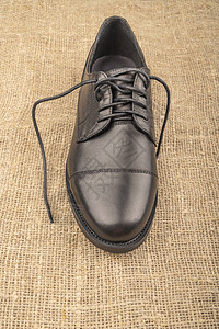 一个黑色皮靴有粗糙布料背景上的带鞋图片