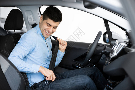 快乐的caucasian男子在汽车上系紧安全带图片