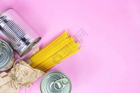 粉红色背景和复制空间的罐头食品金属罐子和黄面条意大利面糊图片
