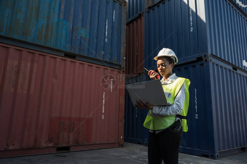 在集装箱货港工作的黑人工头女工拿着笔记本电脑和对讲机装货集装箱非洲码头女员工业务物流进图片