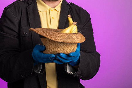 一个男人在她的香蕉里戴顶帽子乞背景图片