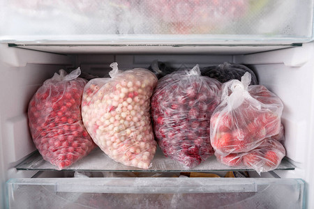 在冰箱的透明塑料袋中冷冻浆果打开装满冷冻浆果和水果的冰箱素食图片