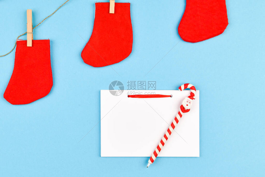 衣夹上的红袜子在蓝色背景上有一堆的空白笔记本从上面查看挂在晾衣绳上图片