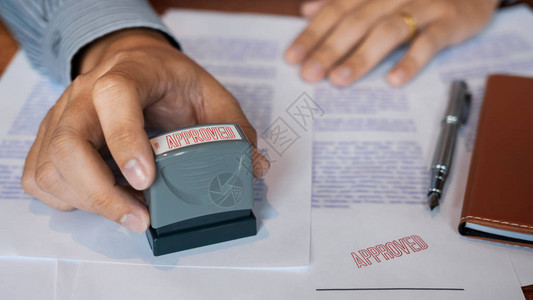 商人手公证人手墨水批准印章在已批准的合同表格文件合同贷款货币概图片