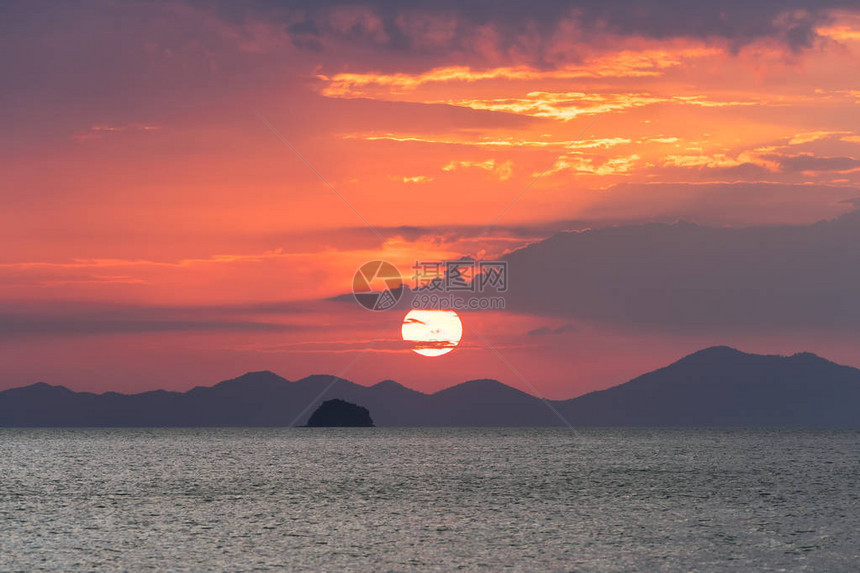 美丽如画的海上日落大红色的太阳圈在海平面上方的山脉和云层的图片