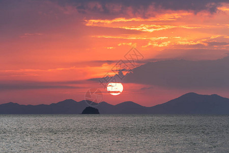 美丽如画的海上日落大红色的太阳圈在海平面上方的山脉和云层的图片