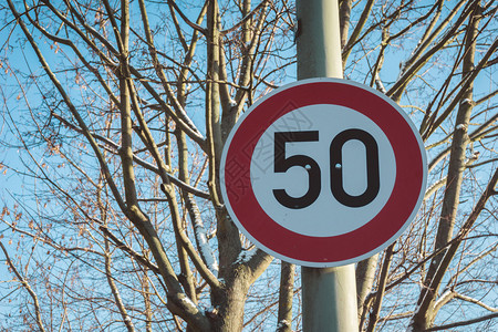 每小时50公里或英里的速度限制标志架在一根柱子上图片