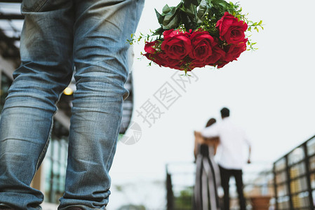 亚洲伤心欲绝的男人拿着一束红玫瑰在看到女人和另一个男人约会时感到悲伤心碎背景图片