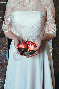 穿婚纱的姑娘手心捧着一个石榴背景图片