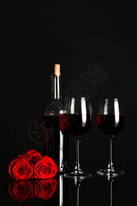 深色背景中带玫瑰花的酒杯和酒瓶图片