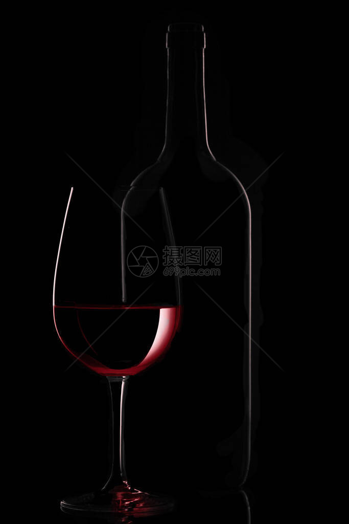 黑色背景中的红葡萄酒瓶和酒杯图片