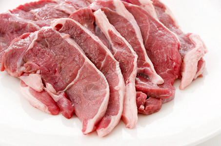 白色背景上的白盘子上的生羊肉背景图片