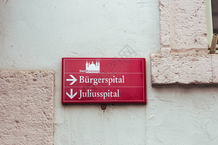 德国维尔茨堡一条街道上为游客准备的红色定向城市旅游标志BurgerspitalengBurger医院背景图片