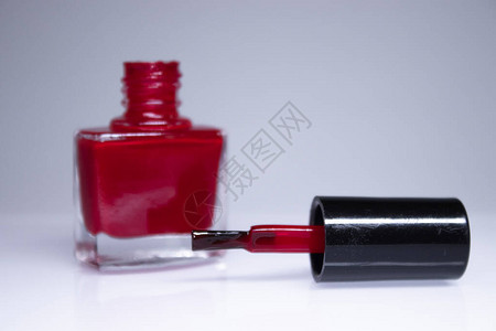 一瓶白色背景上溢出的红色指甲油指甲油指甲修指甲概念隔图片
