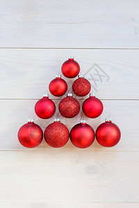 圣诞树由木制背景上的红色圣诞球制成图片