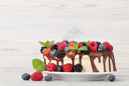 巧克力蛋糕或带浆果的芝士蛋糕在木制桌上图片