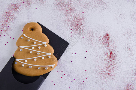 圣诞姜饼圣诞树位于黑色包装和白色上在闪亮的红色闪光和闪发光的图片