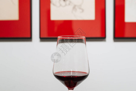 品酒概念照片酒杯与红酒在展览的红框画背图片