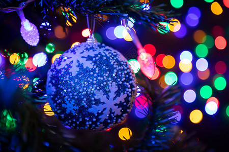 一个蓝色闪亮的圣诞球的特写镜头挂在圣诞树上图片