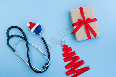 红色圣诞老人帽子礼品盒和圣诞树上的医用听诊器图片