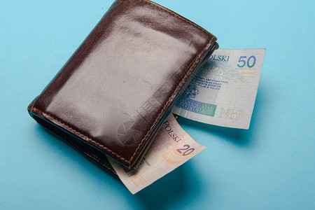 蓝色背景上有钞票的棕色男士皮革钱包图片