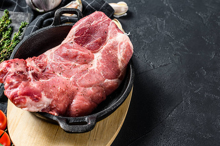 在平底锅里的生猪排牛一块生肉准备好用蔬菜和香料准备黑色背景顶视图片