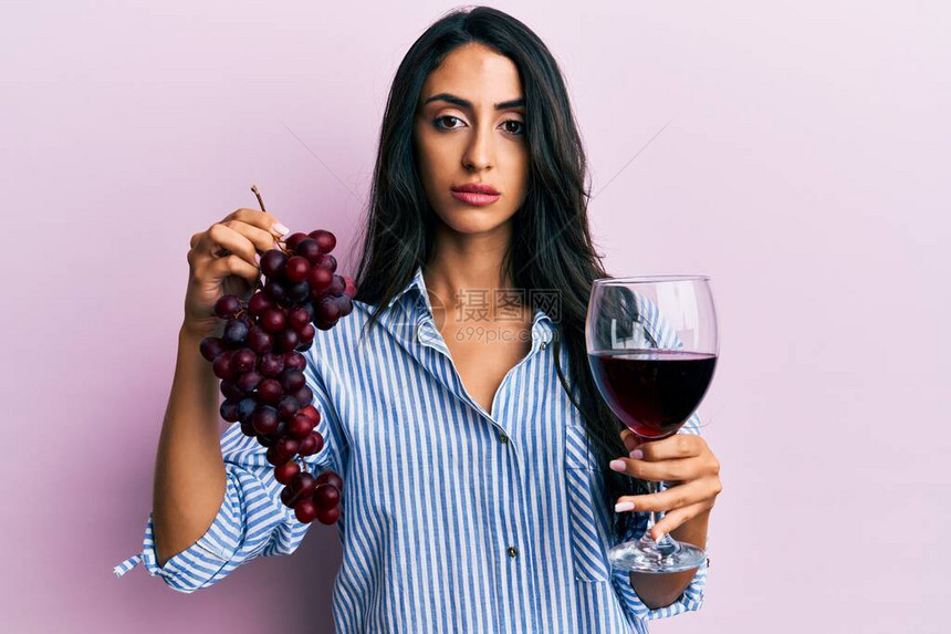 美丽的西班牙女人拿着新鲜葡萄和红酒的枝子图片