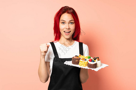 手持松饼的糕点厨师在粉红背景上被孤立图片