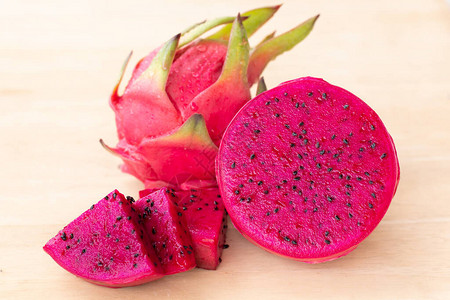 新鲜的火龙果在木质背景上切片或成熟的火龙果红色图片