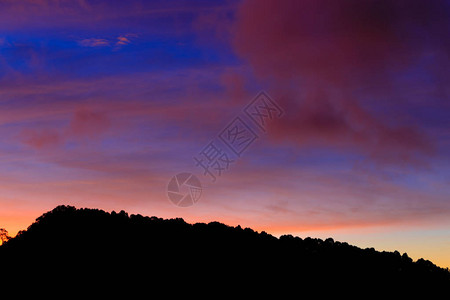 黄昏或黎明时分的紫色粉红色橙色的暮色天空与剪影山图片