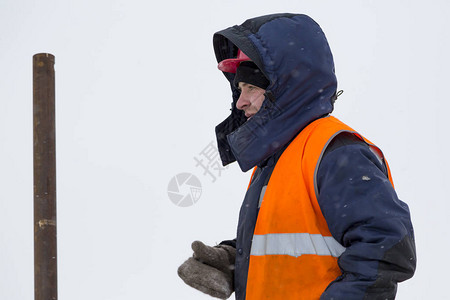 一名穿着蓝色夹克的工人头上戴头罩的蓝背景图片