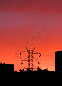 城市深红色日落背景下的高压输电线路图片
