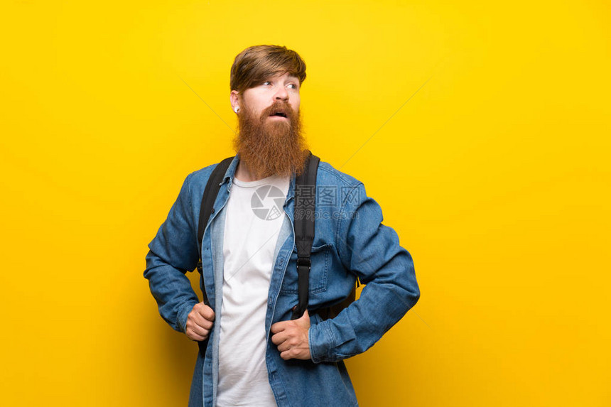 长胡子的红头人用背包在孤立的黄图片