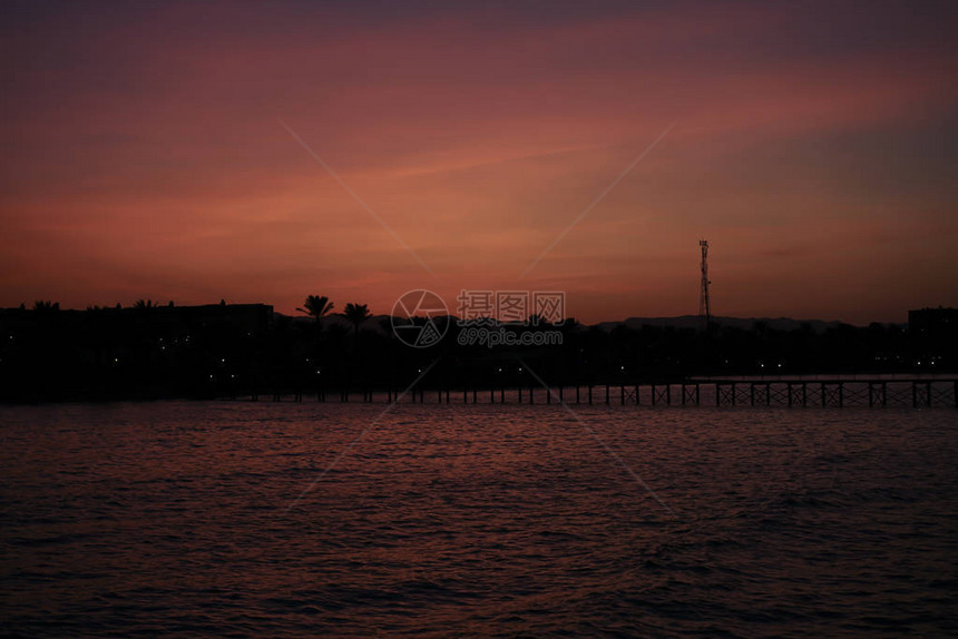 紫色日落与黄昏时的浮舟桥酒店和棕榈图片