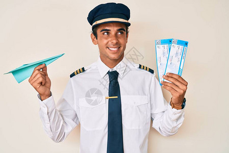 身穿飞机驾驶制服的西班牙年轻人持有纸机和登机牌图片
