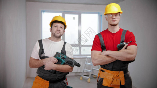 两名合适的工人站在公寓的手持仪器草图片