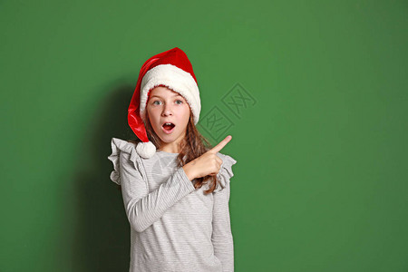 穿着圣诞老人帽子的惊喜小女孩指着一些图片