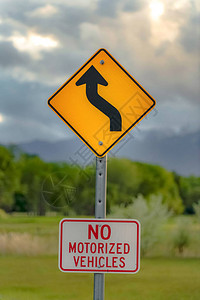 前方蜿蜒道路标志和禁止机动车辆标志的垂直特写视图图片