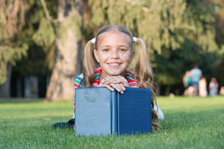 上学时间培养积极成长和取得成就的有爱心的学习者小孩看书可爱的书虫女学生阅读故事放松绿色草坪可爱的背景图片