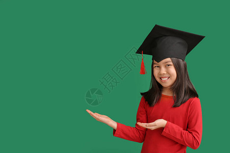 戴着毕业帽子的小女孩在彩色背景上图片